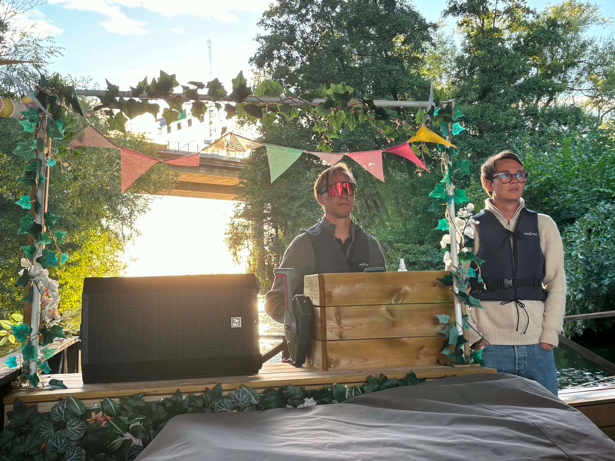 Discjockey vid ljudanläggningen på Festflotten i kvällssol, bro syns i bakgrunden
